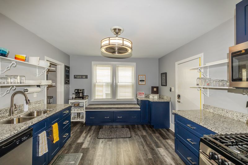 Navy kitchen with granite counters, gas range and open shelving